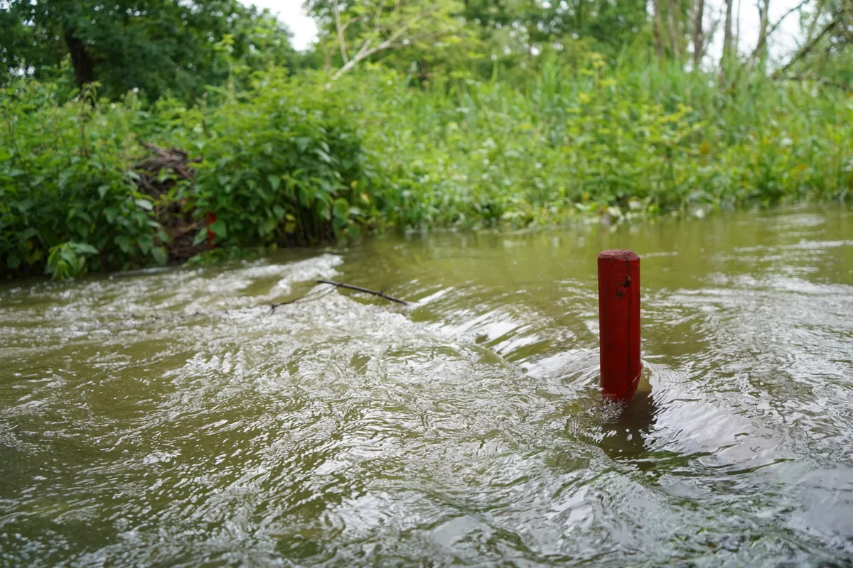 Ein Bach, aus dem Wasser ragt in roter Pfosten